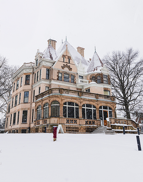 exterior view of a gilded age mansion covered in a dusting of snow